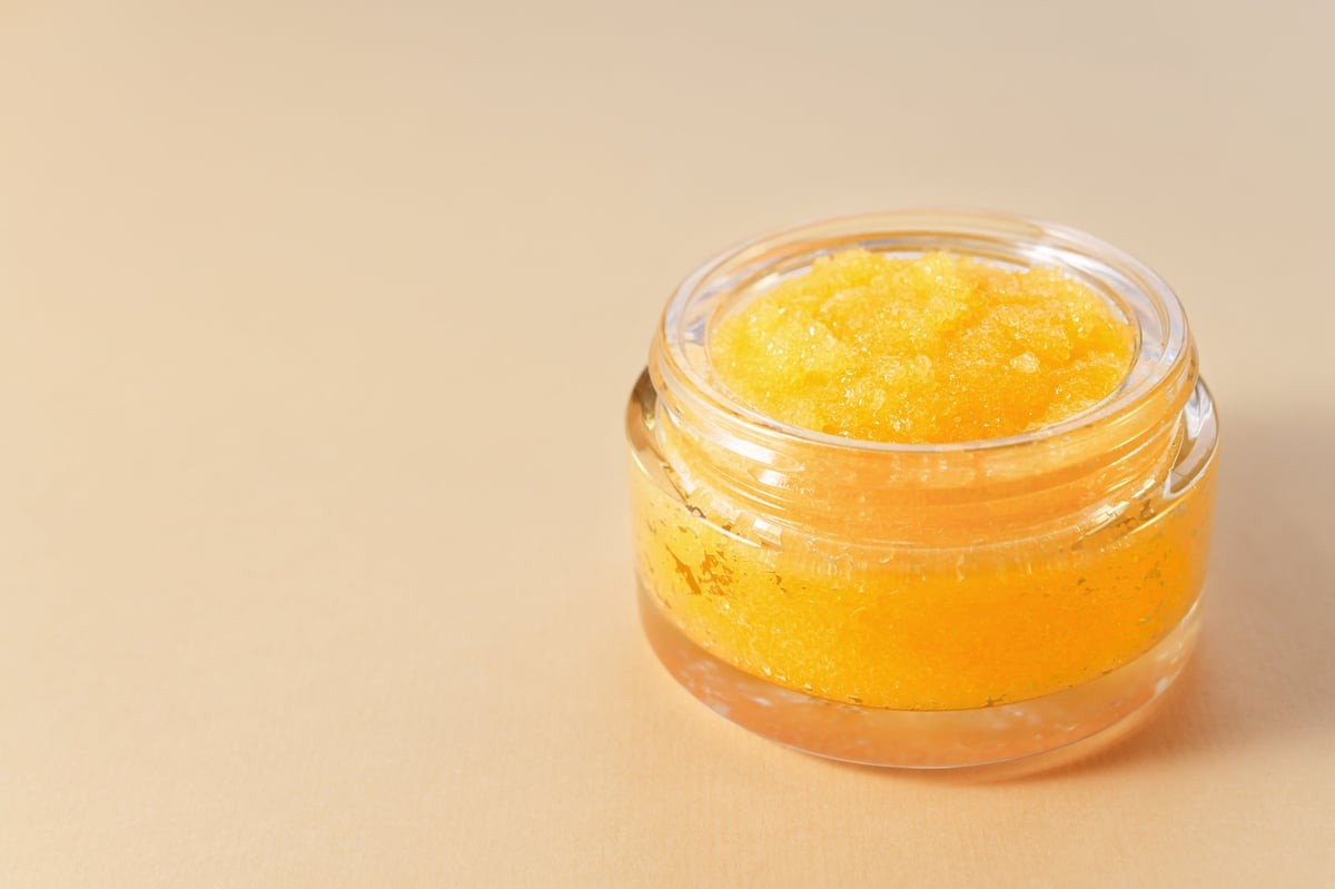 Means for cleansing and peeling the skin in a glass jar on a uniform background with a copy space, beauty spa