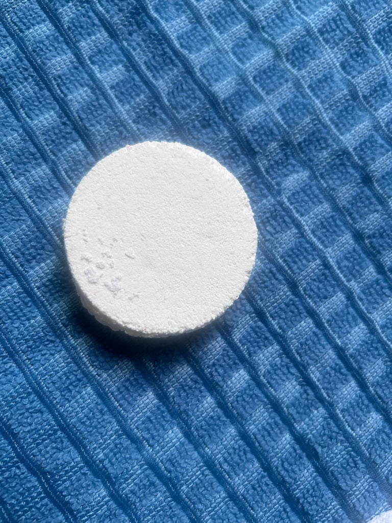 White round tablet or pill on a blue textured fabric background